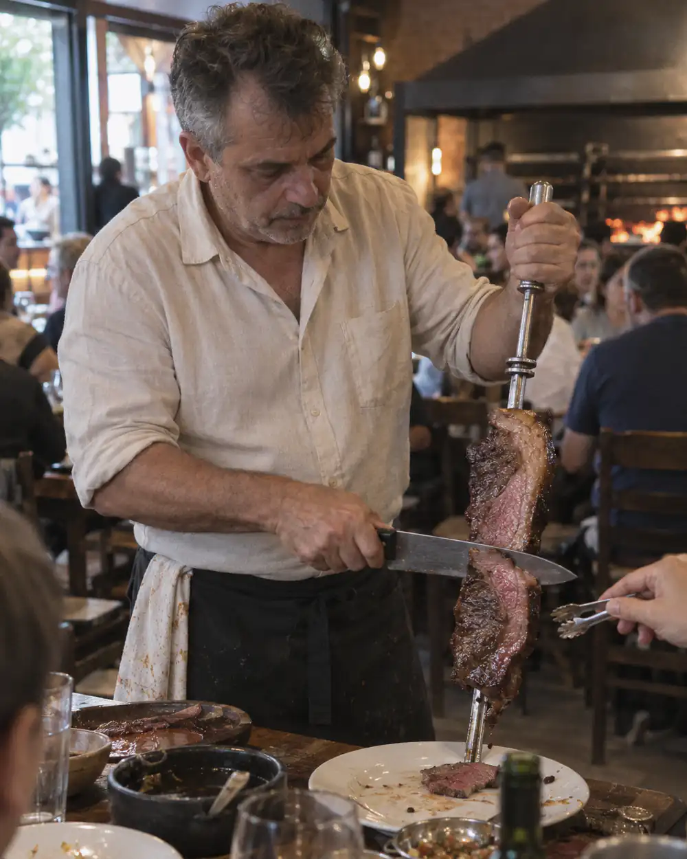 A churrascaria owner carving picanha at the table